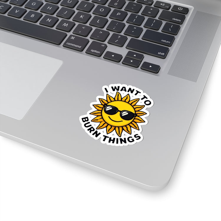 Laptop with a sun-shaped sticker that says 'I want to burn things' on a white background