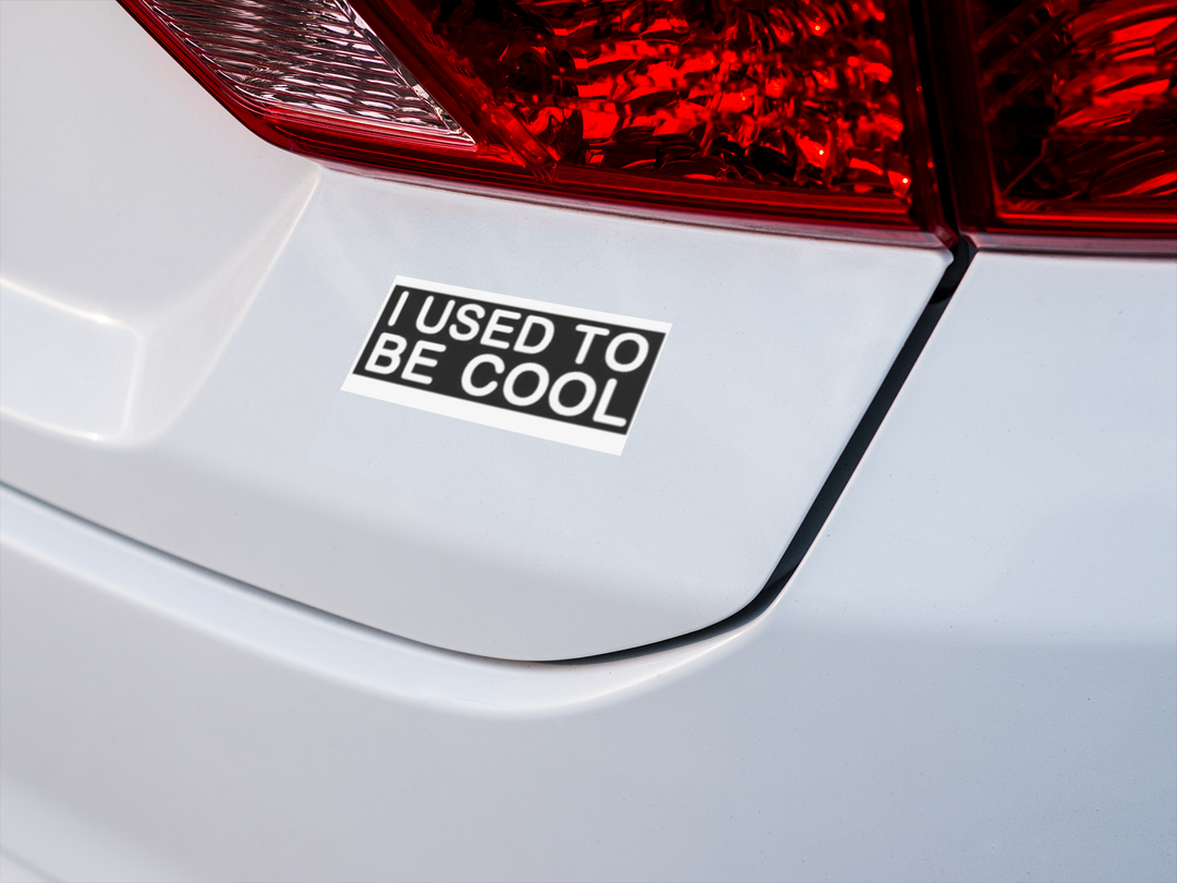Sticker on a car tailgate reading 'I USED to be Cool' with red taillights in the background.