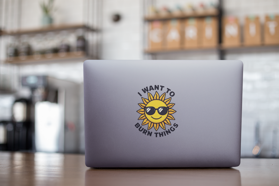 Laptop with a sun-themed sticker on a blurred cafe background
