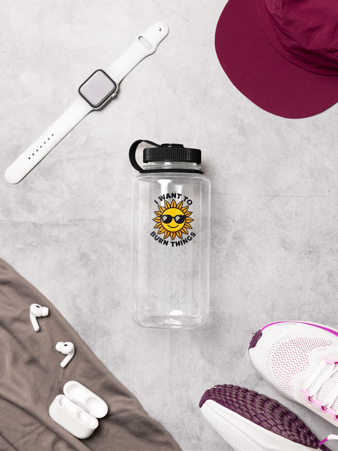 Clear water bottle with sun design, white earbuds, white watch, maroon hat, and white sneakers on a gray surface.