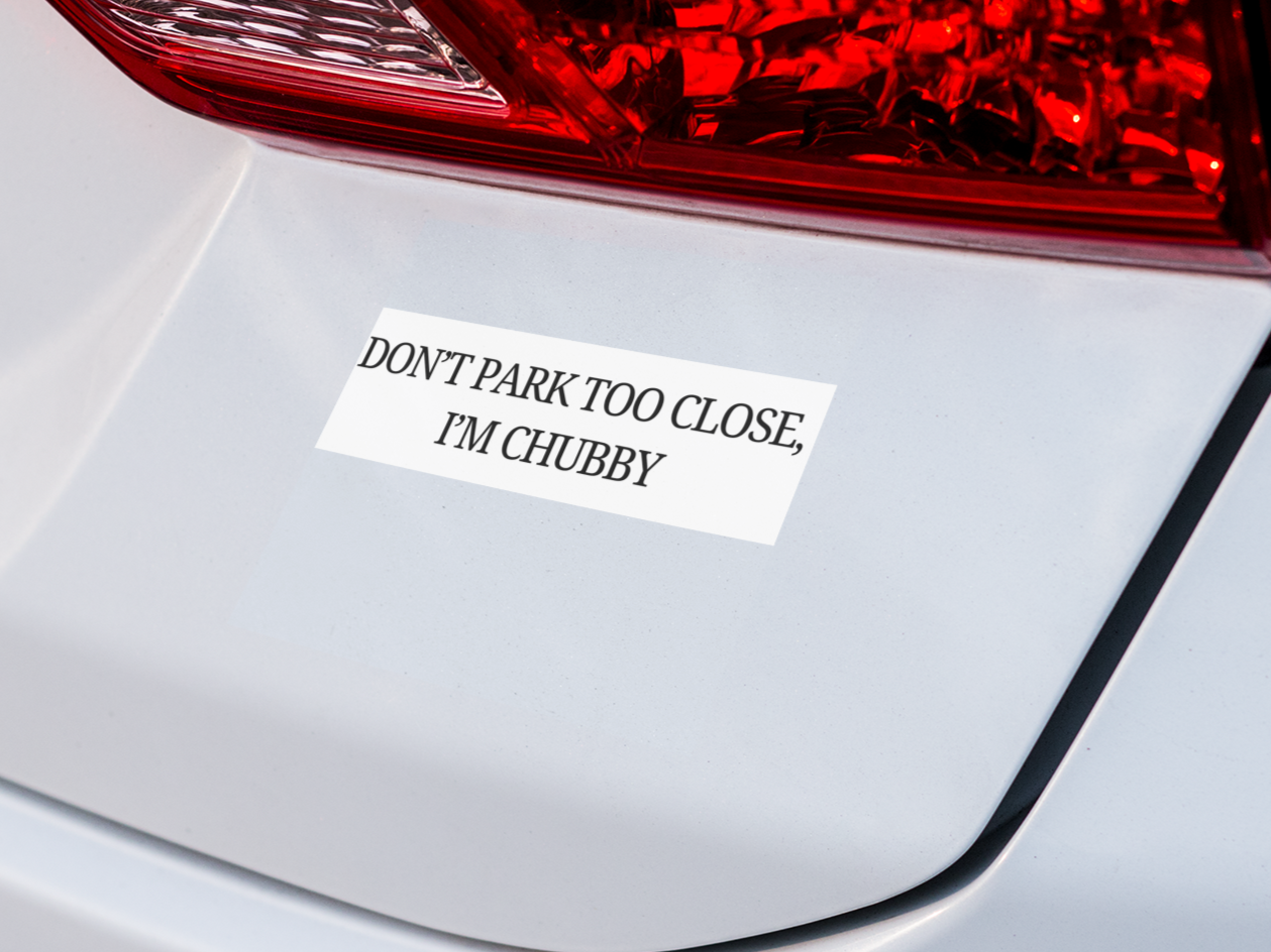 Car bumper with a humorous sticker reading 'Don't park too close, I'm chubby' on a white car.
