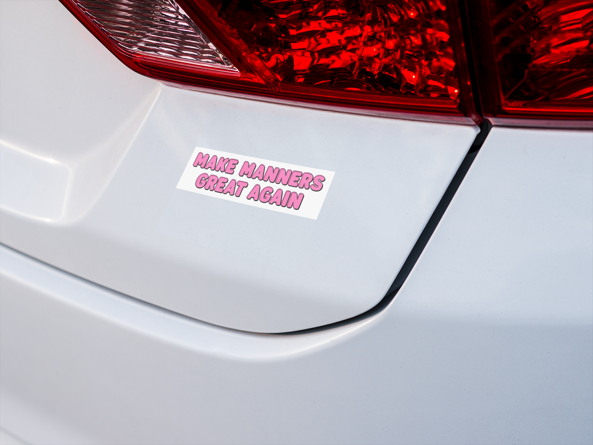Car bumper with a sticker reading 'Make Manners Great Again' on a white car.