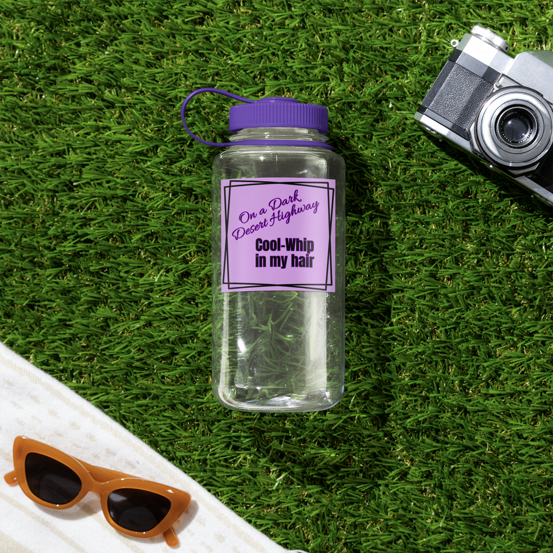 Clear water bottle with purple label on grass with sunglasses and camera