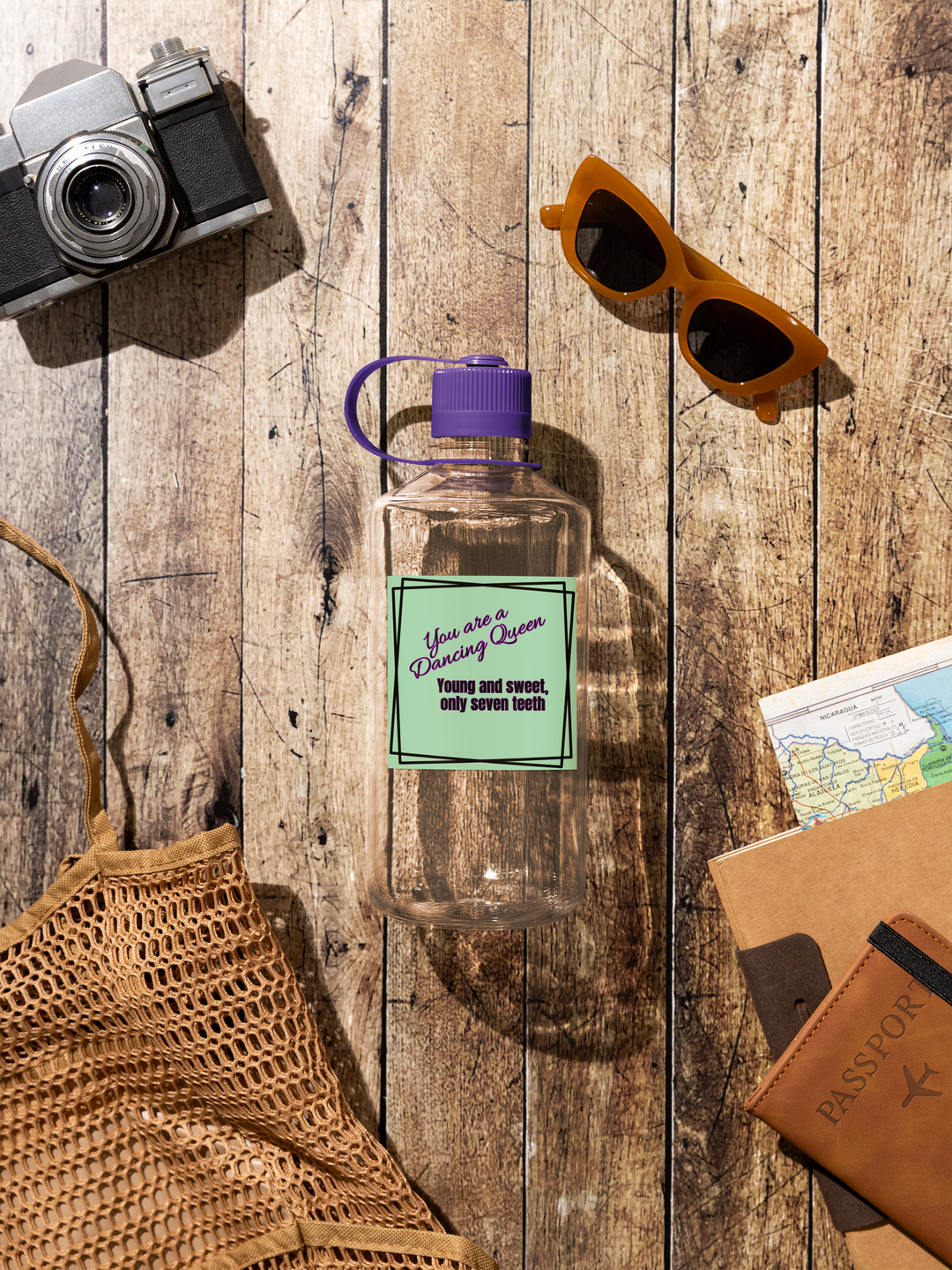 Clear water bottle with purple cap on a wooden surface with camera, sunglasses, and passport holder.