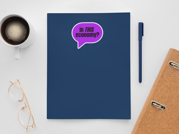 Blue notebook with a purple speech bubble graphic, coffee cup, glasses, and pen on a white surface