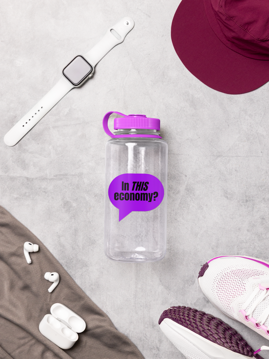 Clear water bottle with purple lid and speech bubble graphic on a gray surface with accessories.