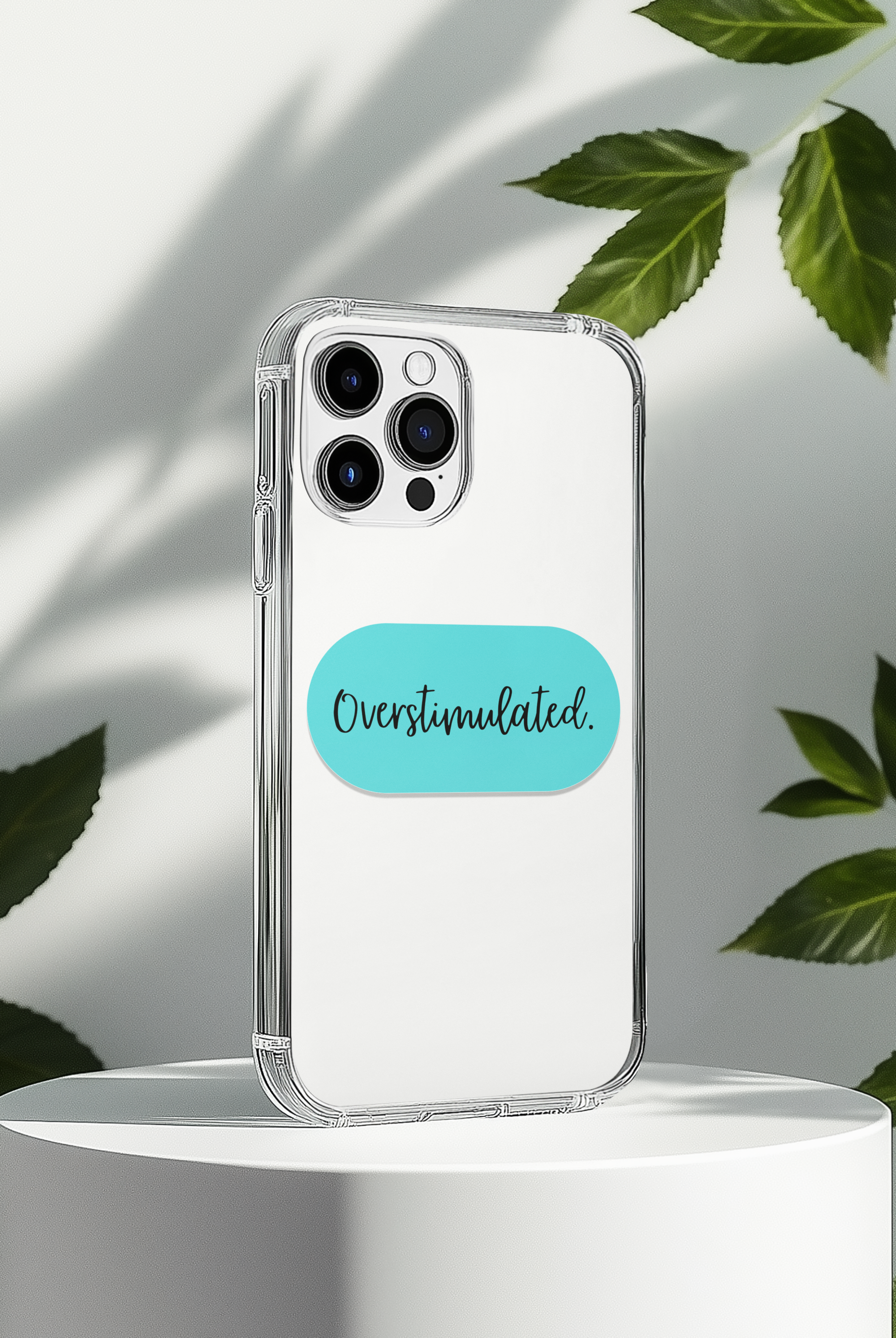 Phone case with 'Overstimulated' sticker on a white background with leaves