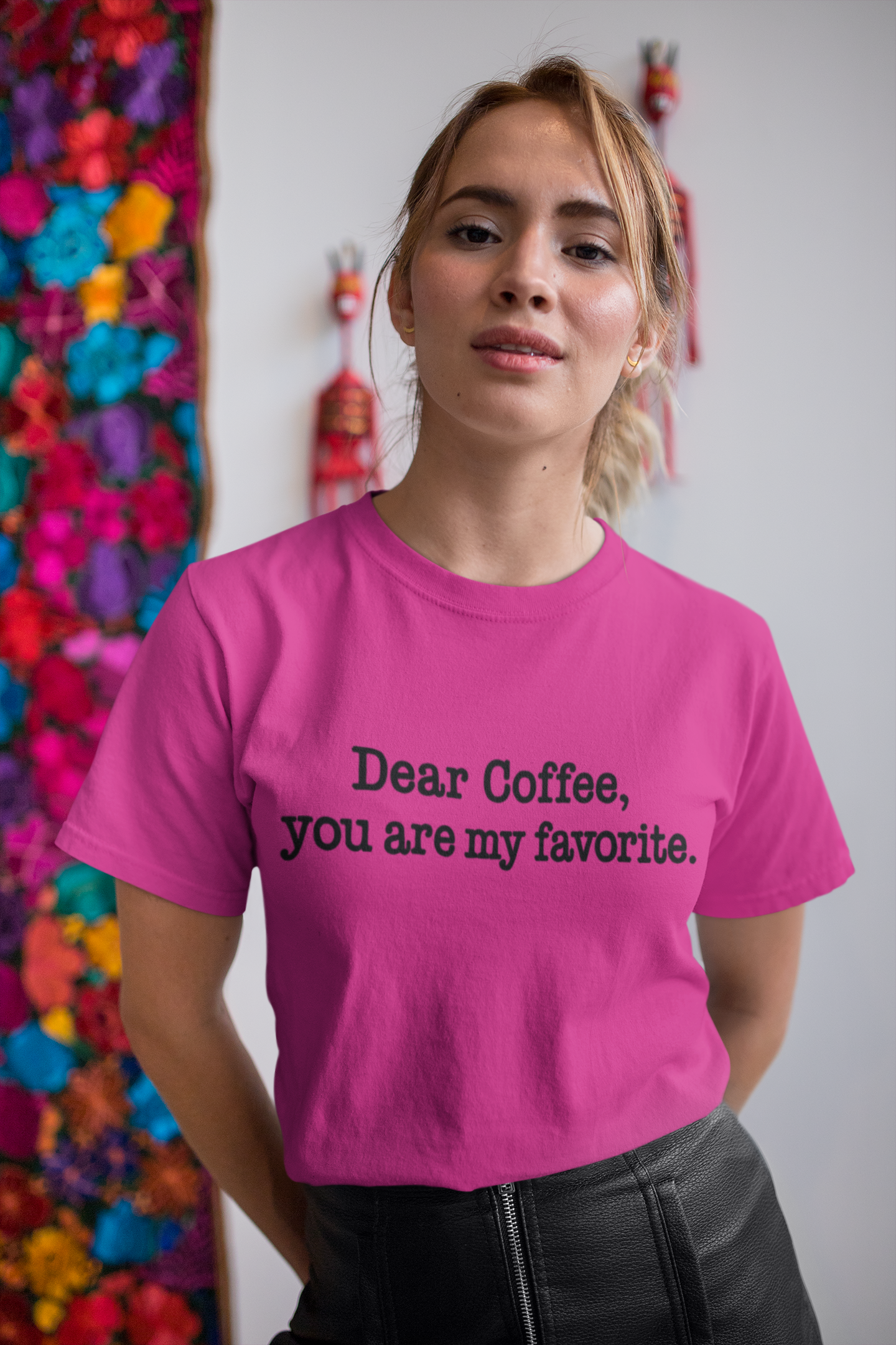 Person wearing a pink t-shirt with text, Dear Coffee, You are my favorite. standing in front of colorful flowers.