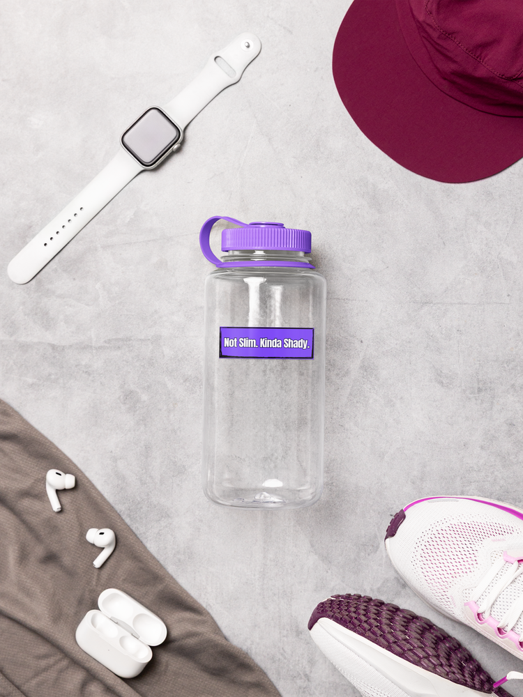Clear water bottle with purple lid and Sticker - "Not Slim, Kinda Shady" white sneakers, maroon hat, and wireless earbuds on a light gray surface.