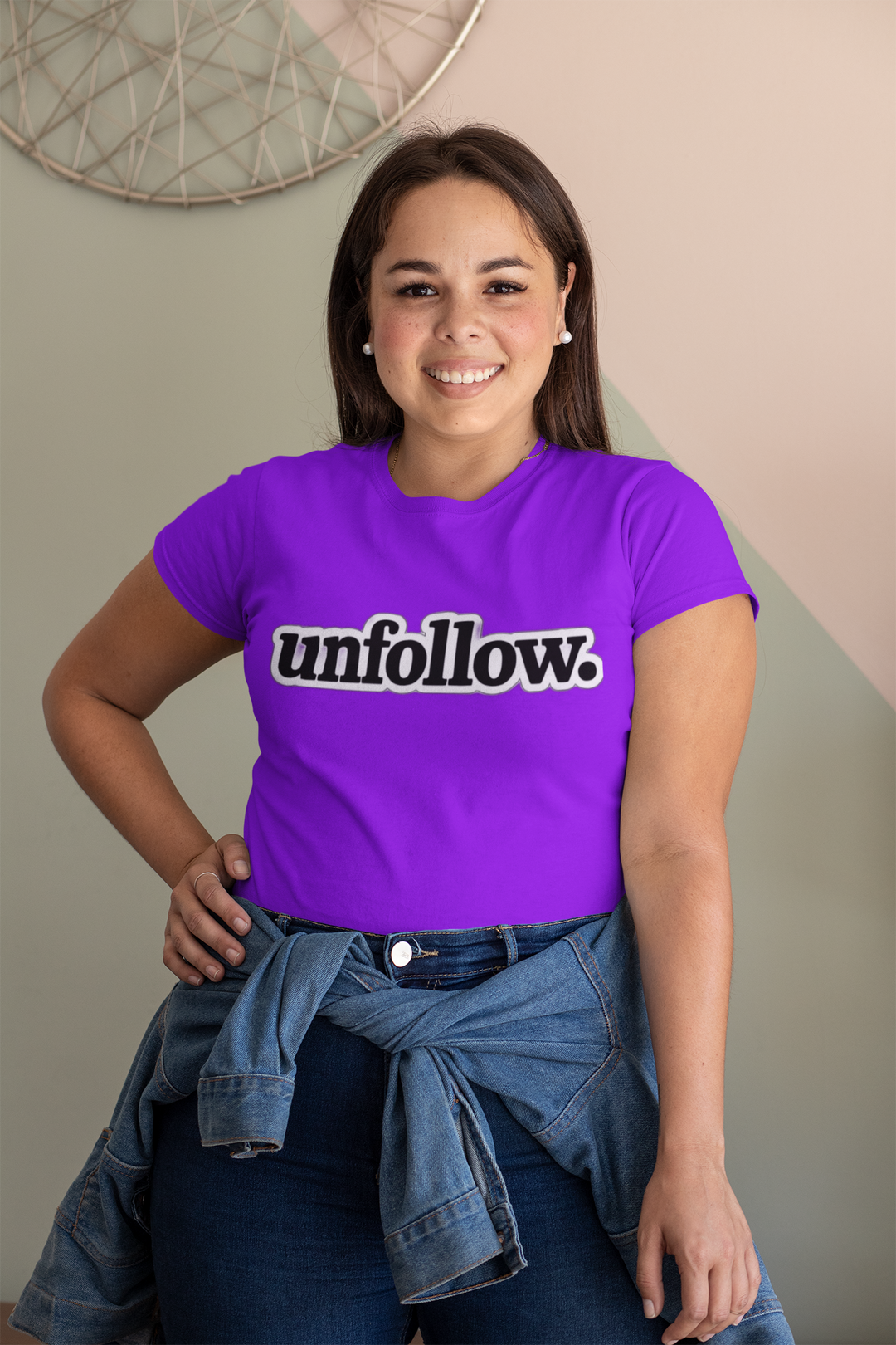 Person wearing a purple t-shirt with 'unfollow.' text, standing indoors.