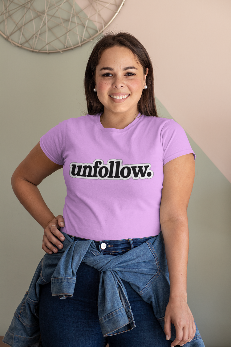 Person wearing a purple t-shirt with 'unfollow.' text, standing against a neutral wall.