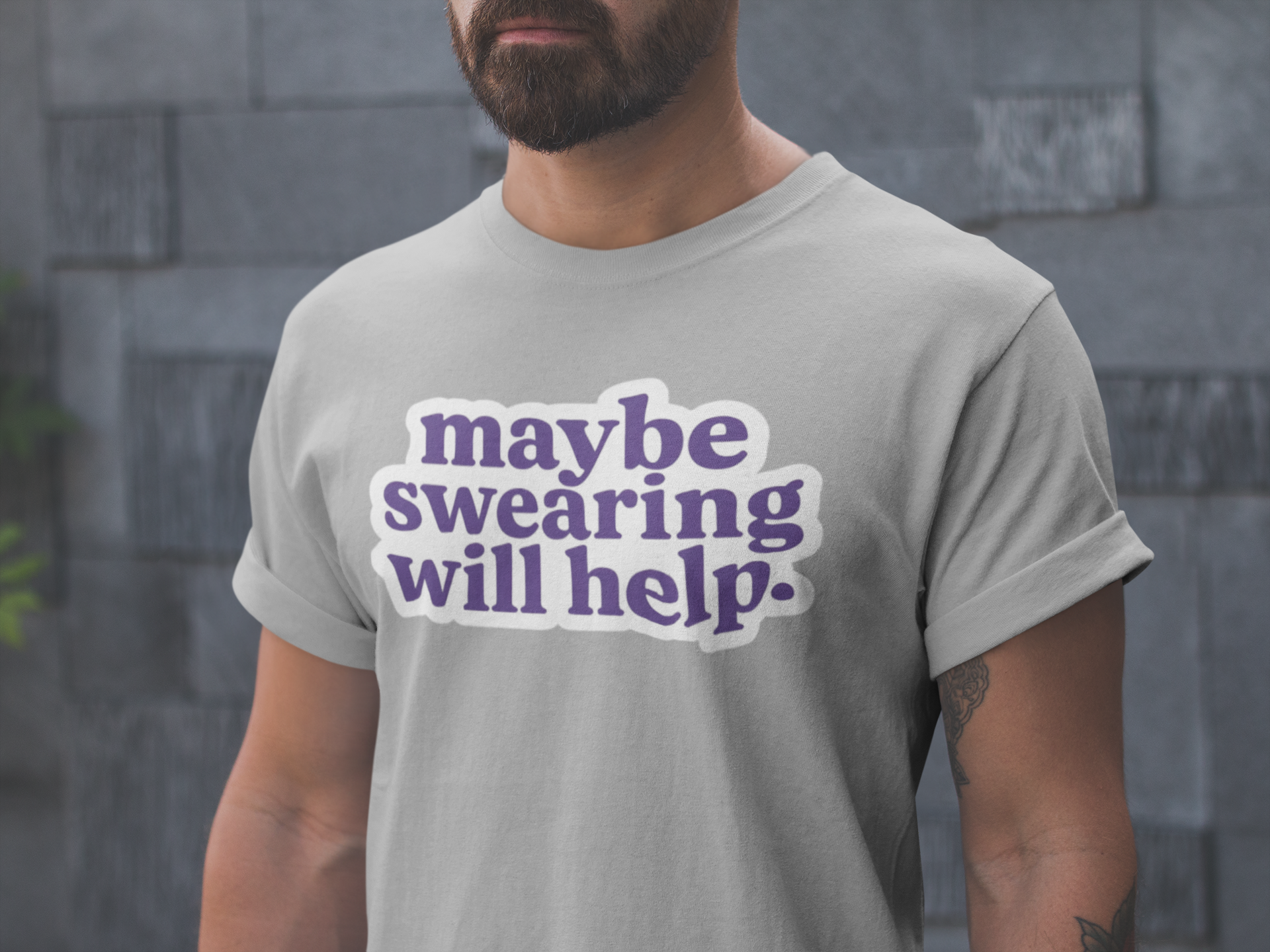Person wearing a gray t-shirt with 'maybe swearing will help.' text in purple.