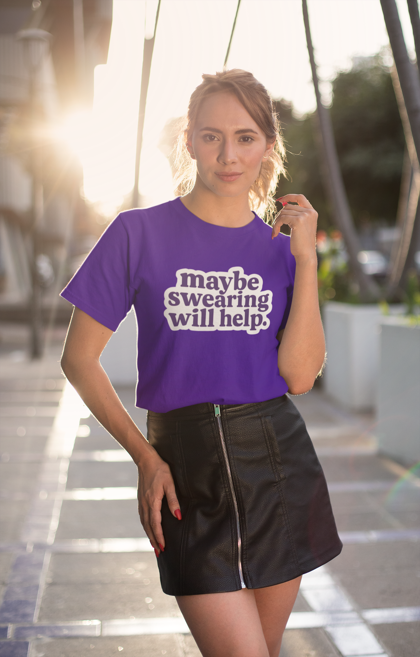 Woman wearing a purple t-shirt with maybe swearing will help text in an urban setting