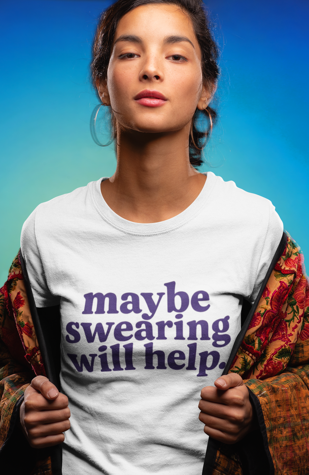 Person wearing a white t-shirt with 'maybe swearing will help.' text against a blue gradient background