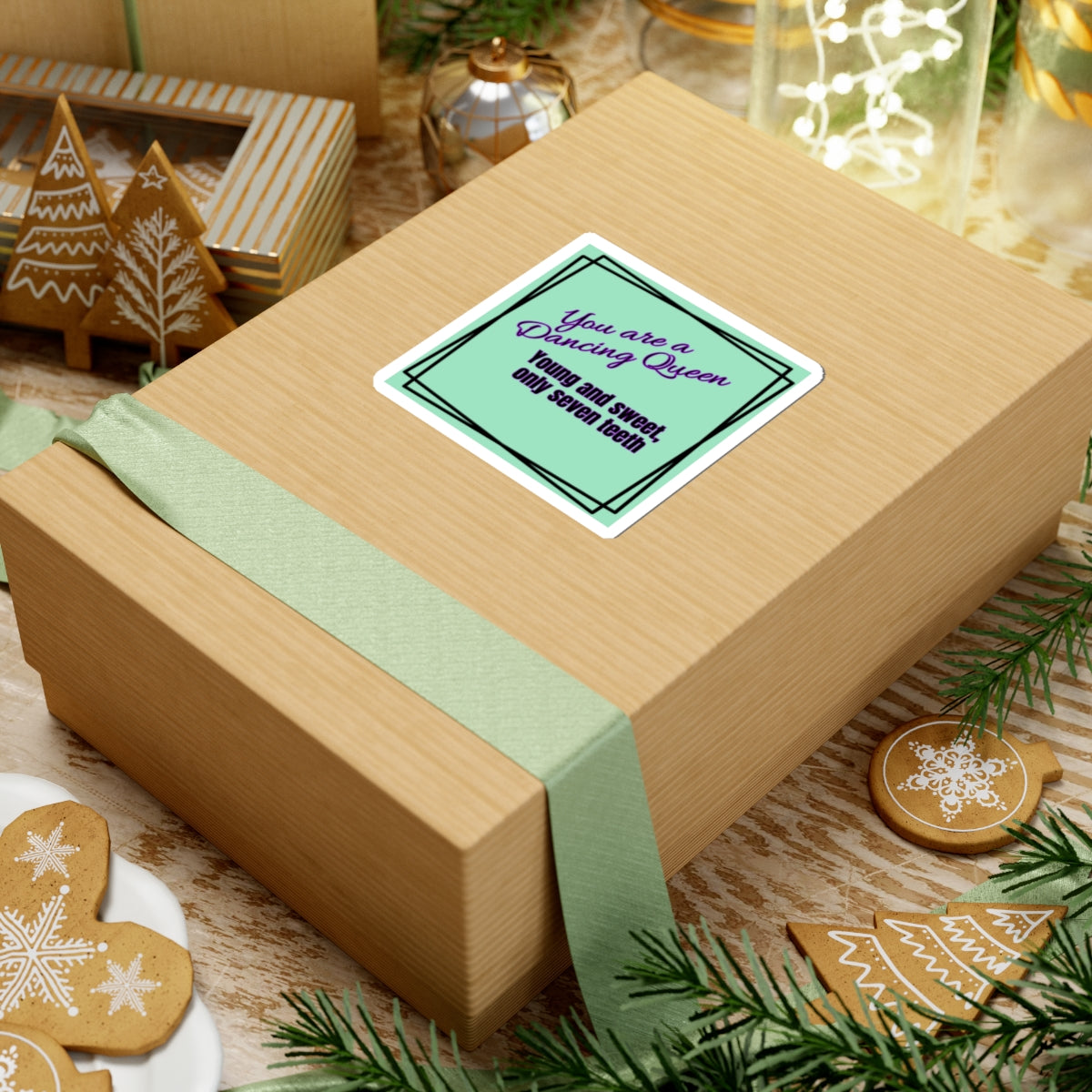 Wooden gift box with a green ribbon and a card on a festive background with cookies and decorations.
