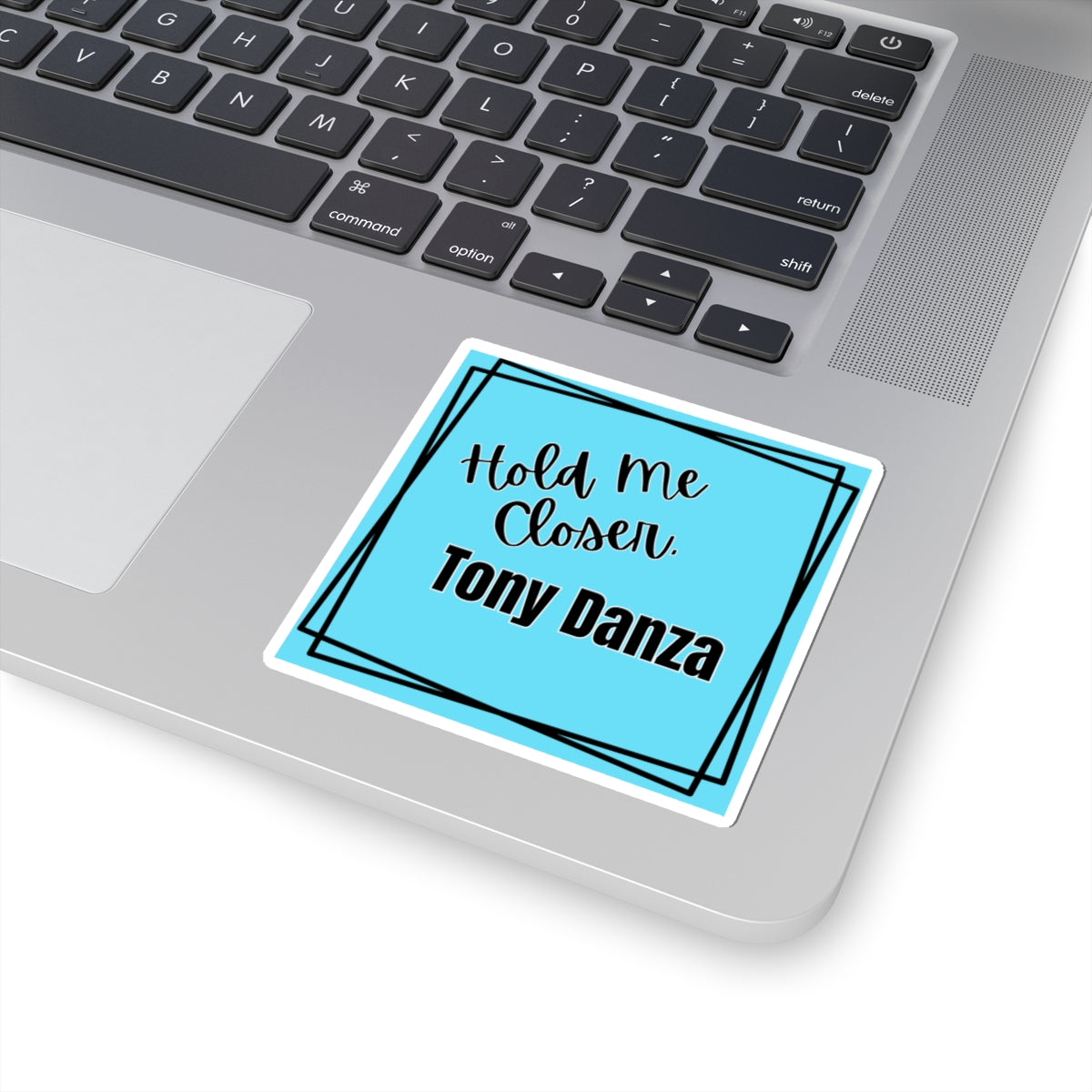 Laptop with a sticker that says 'Hold Me Closer. Tony Danza' on the palm rest area.