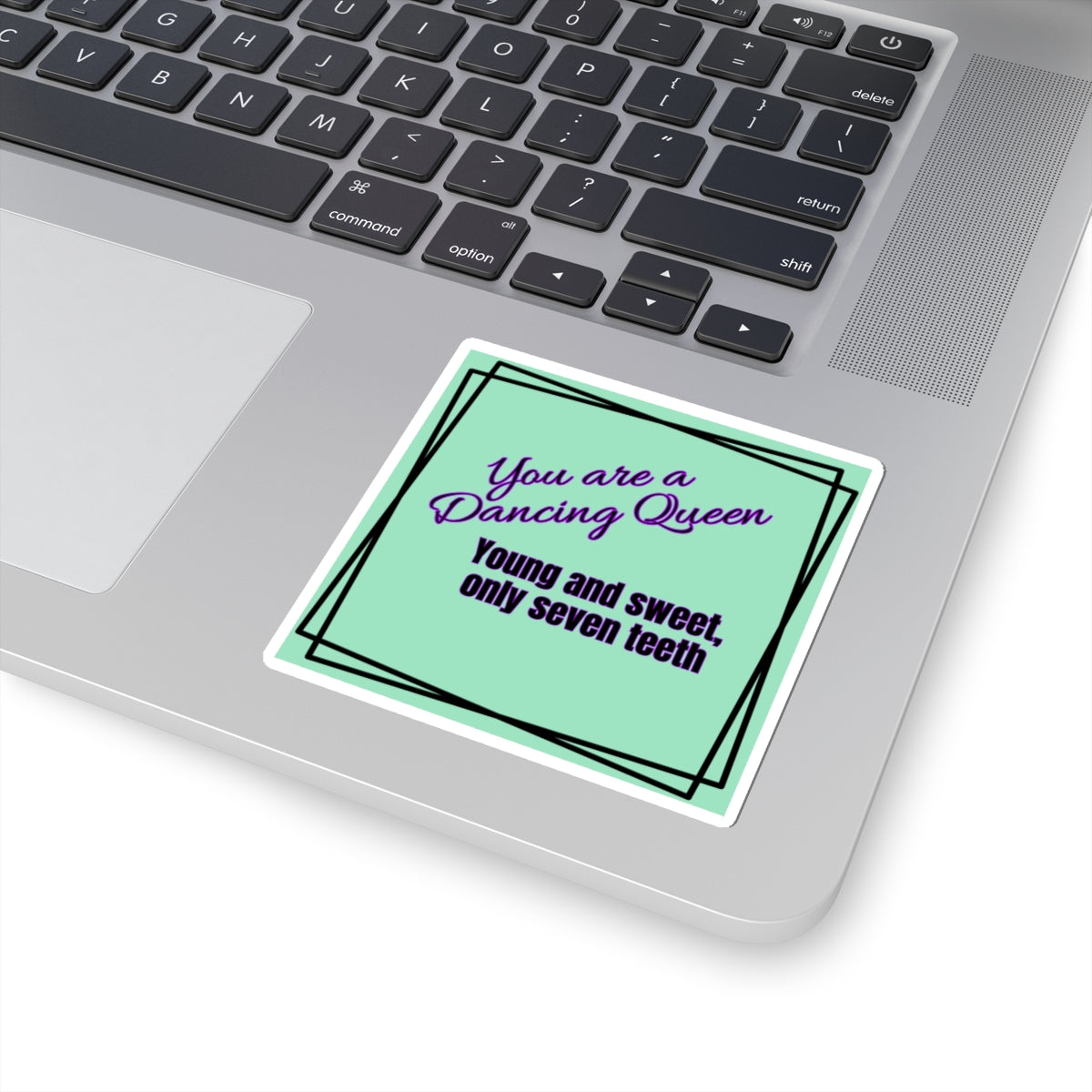 Laptop with a sticker reading 'You are a dancing queen, young and sweet, only seven teeth' on the palm rest area.
