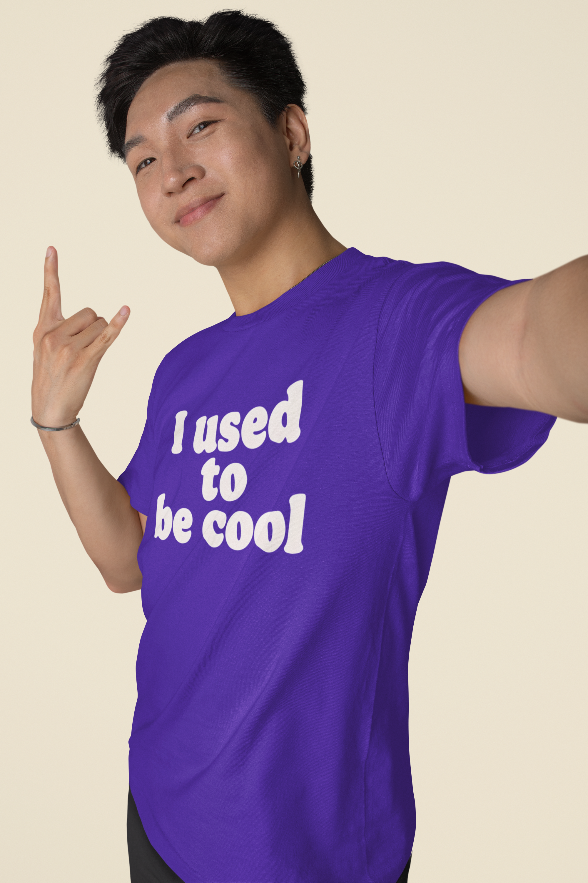 Person wearing a purple t-shirt with 'I used to be cool' text on a beige background