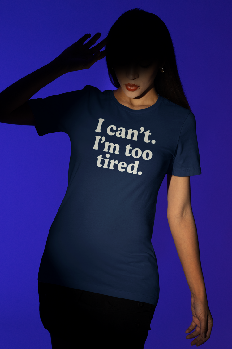 Person wearing a navy blue t-shirt with 'I can't. I'm too tired.' text on a solid background