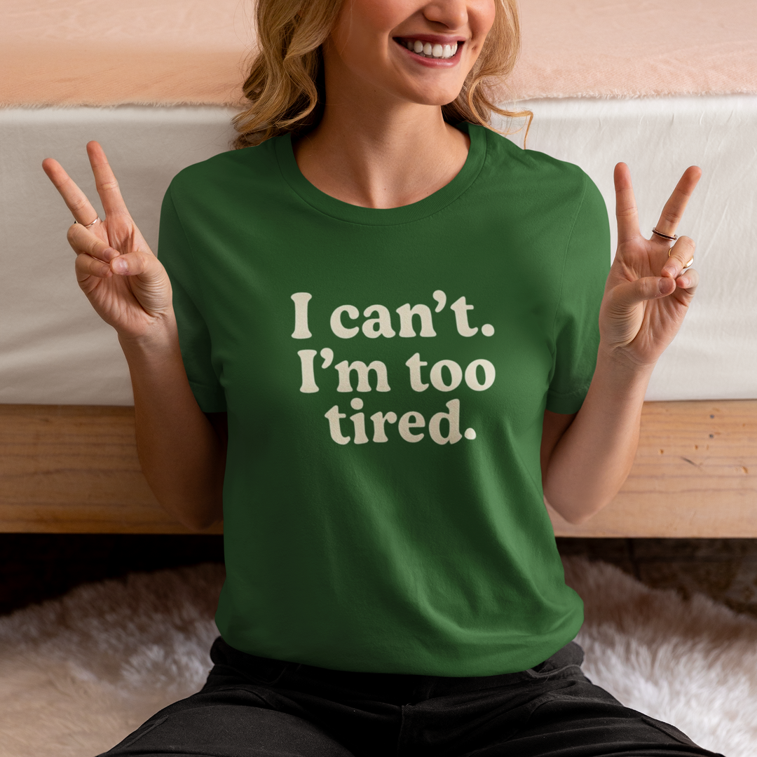 Person wearing a green t-shirt with 'I can't. I'm too tired.' text, making peace signs.