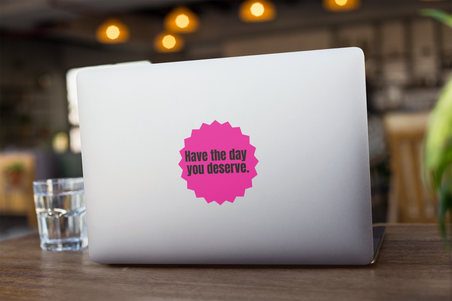 Laptop with a pink "Have the day you deserve" sticker on a wooden table