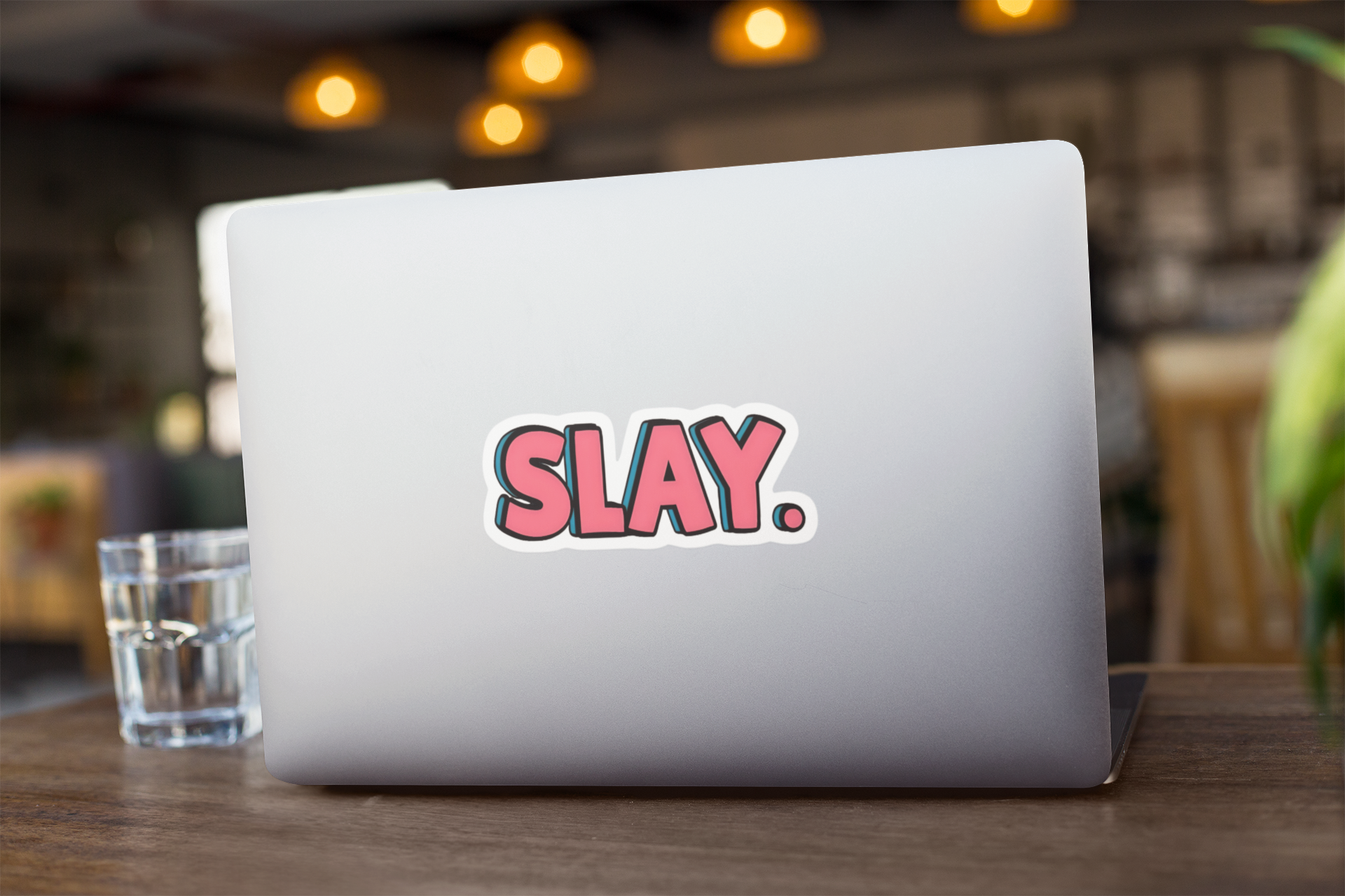 Laptop with 'SLAY.' sticker on a wooden table with a blurred background