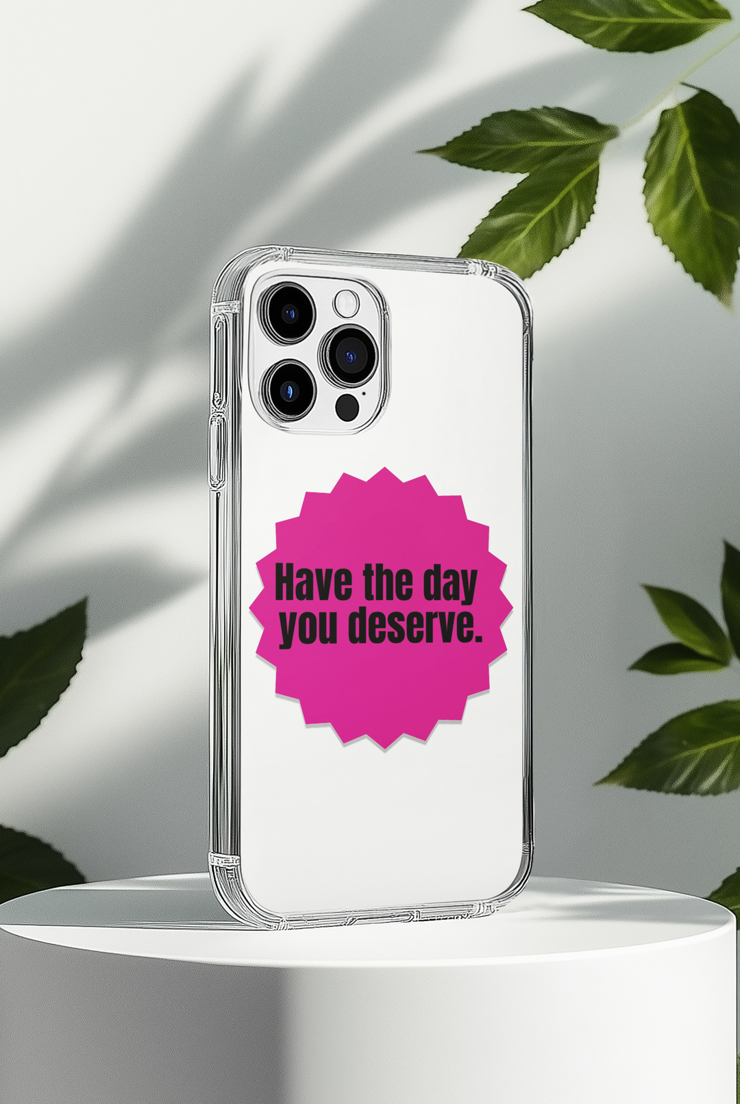 Phone case with "Have the Day You Deserve" quote on a white background with leaves