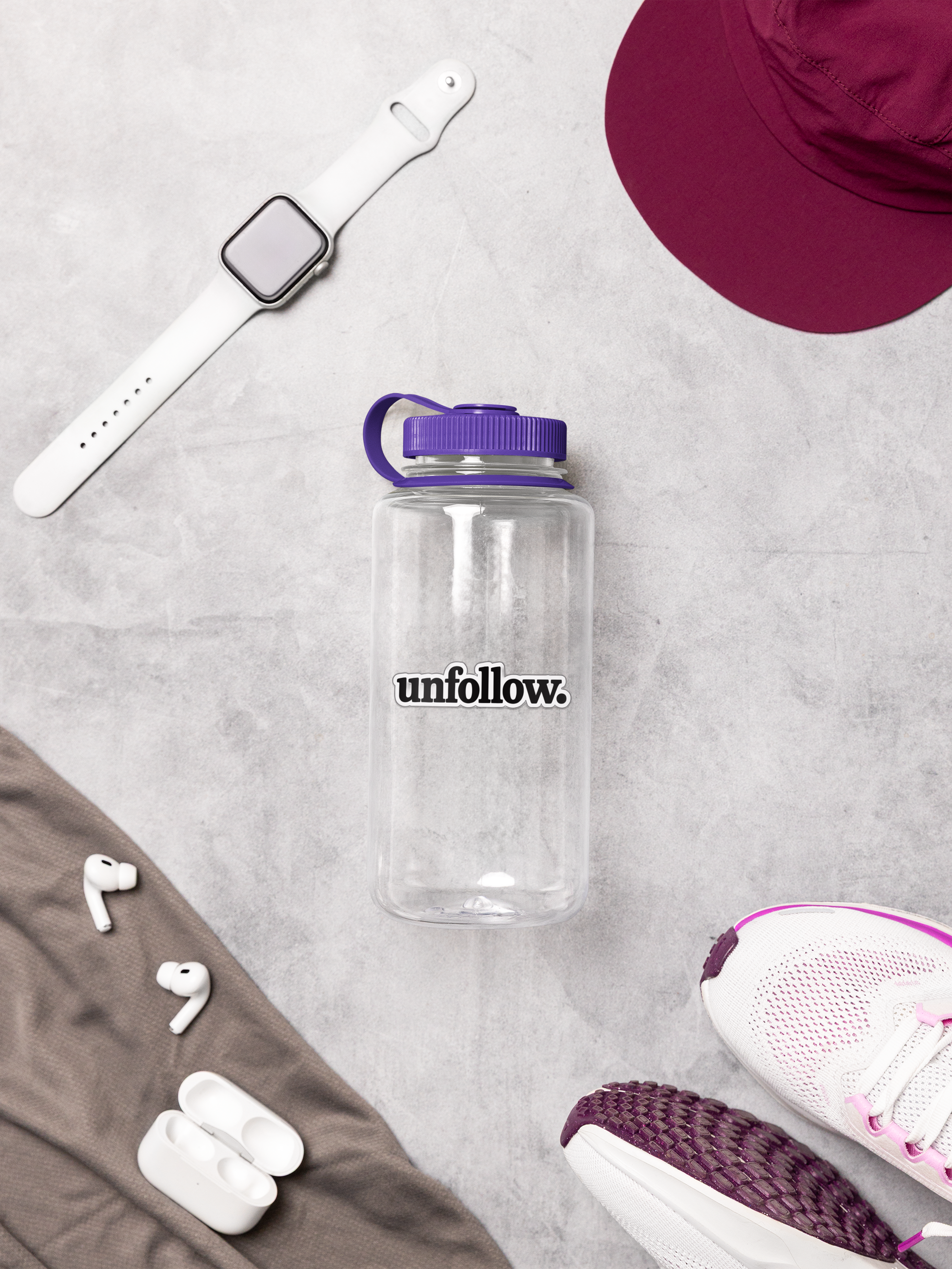 Clear water bottle with purple lid labeled 'unfollow', white smartwatch, red cap, white earbuds, and pink and white sneaker on gray surface.
