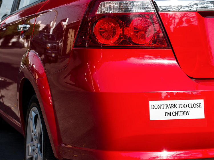 Red car with a humorous license plate on a blurred background