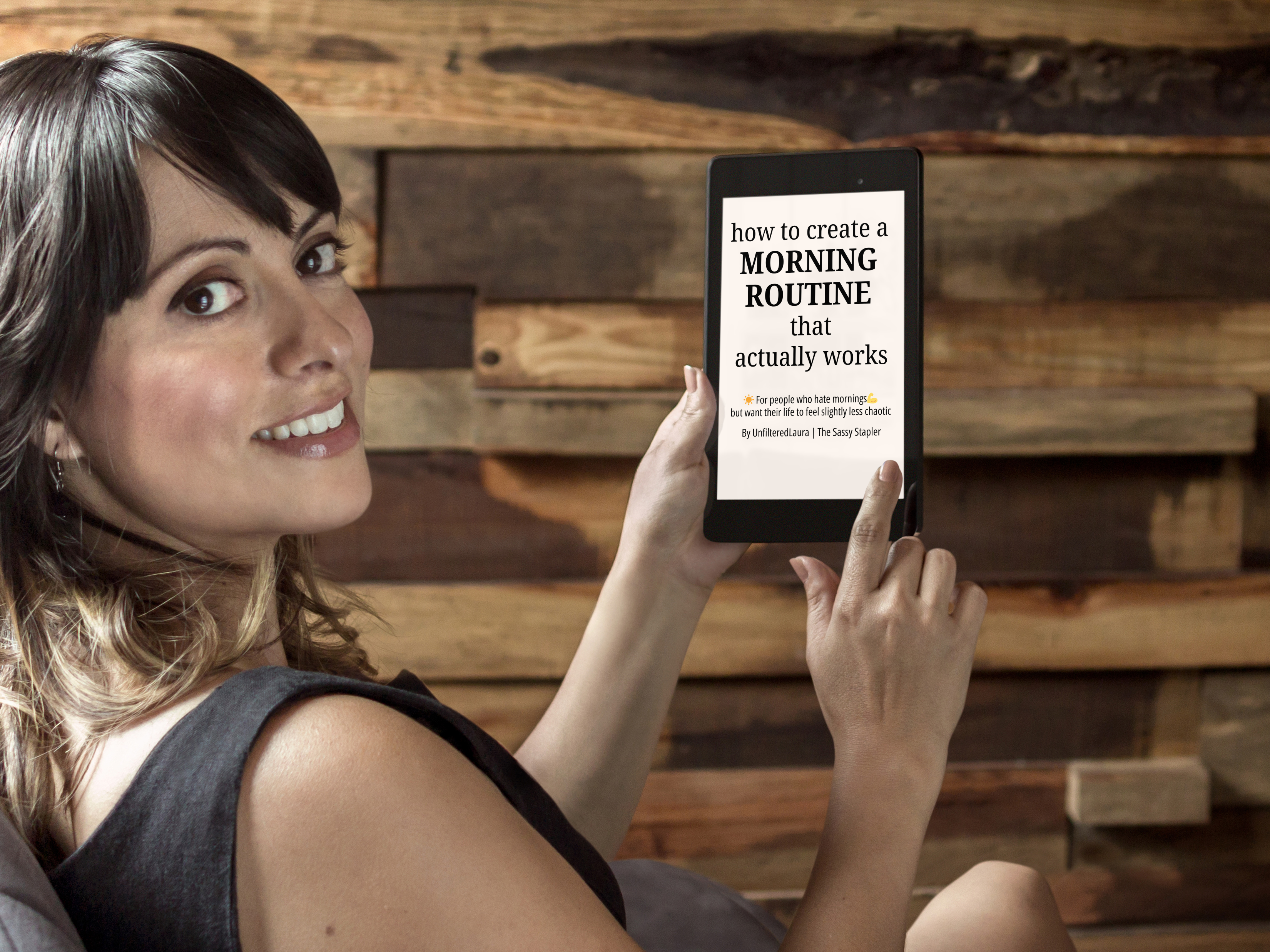 Woman holding a tablet with text on screen against a wooden wall